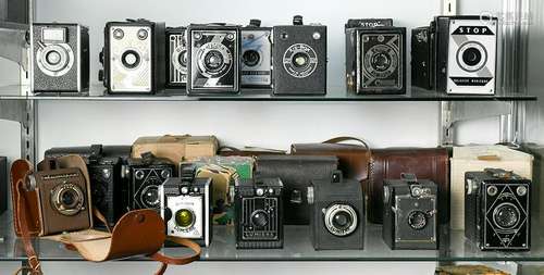 Two shelves of antique French box cameras