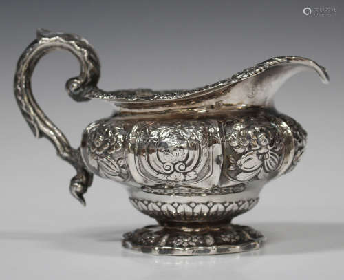 A George IV Irish silver jug of circular ogee form, decorated in relief with foliate and scroll