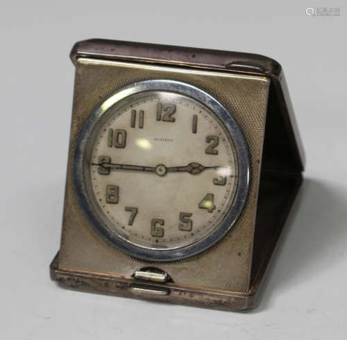 A George V silver cased travelling bedside clock of rectangular form with engine turned