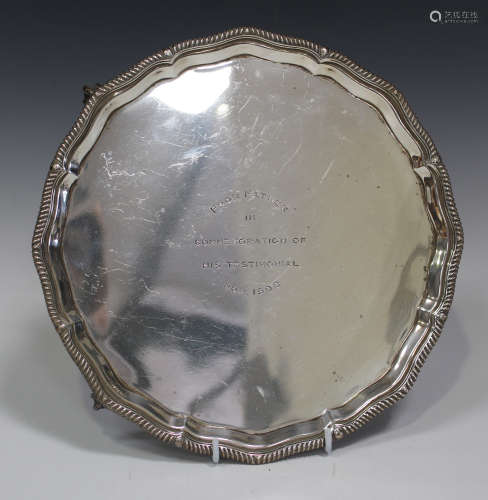 An Edwardian silver circular salver with gadrooned piecrust rim, raised on claw and ball feet,