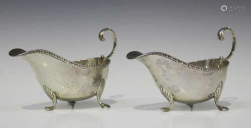 A pair of Edwardian silver sauce boats, each with gadrooned rim and scroll handle, on stylized