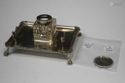 A George V silver inkstand of rectangular form with gadrooned rim and pen rest, raised on claw and