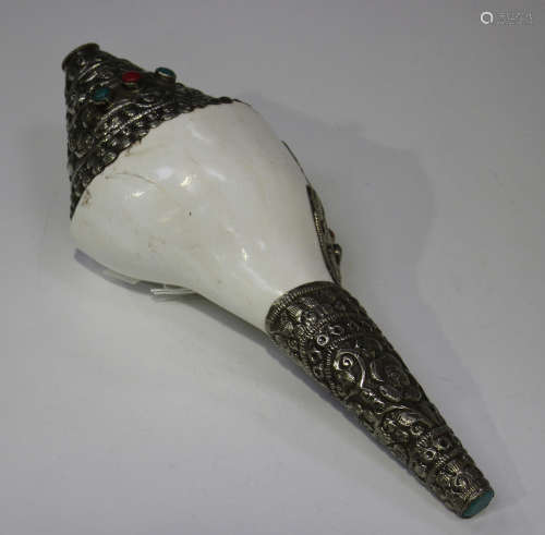 A Tibetan style metal mounted conch shell, the plated mounts with embossed decoration, length 26cm.