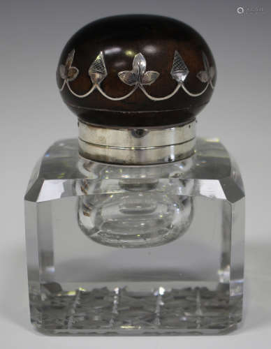 An early 20th century white metal mounted ebonized and cut glass inkwell, the domed hinged lid