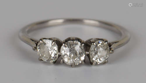 A diamond three stone ring, claw set with a row of cushion shaped diamonds, ring size approx K1/2,