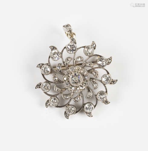 An Edwardian diamond pendant brooch in a circular swirling design, collet set with the principal