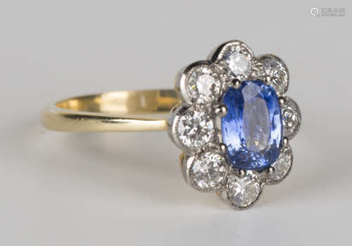 A gold, sapphire and diamond oval cluster ring, claw set with an oval cut sapphire within a surround