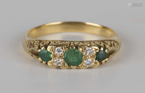 A gold, emerald and diamond ring, mounted with three circular cut emeralds alternating with two