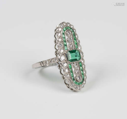A platinum, emerald and diamond open panel shaped ring, mounted with a cut cornered rectangular