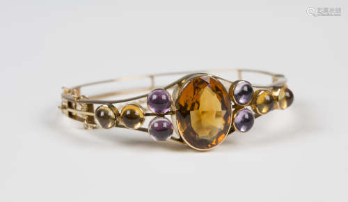 A gold, citrine and amethyst set oval hinged bangle, the front mounted with the principle oval cut