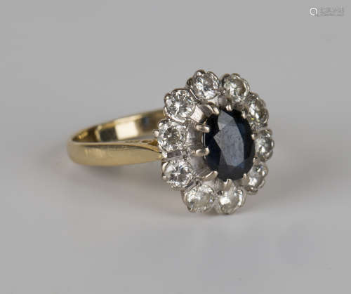 An 18ct gold, sapphire and diamond oval cluster ring, claw set with an oval cut sapphire within a