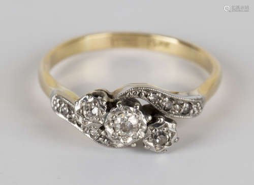 A gold, platinum and diamond three stone ring, mounted with cushion shaped diamonds in a cross-