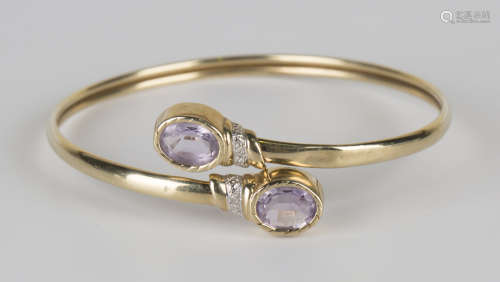 A 9ct gold, amethyst and diamond bangle, collet set with two oval cut pale amethysts and two small