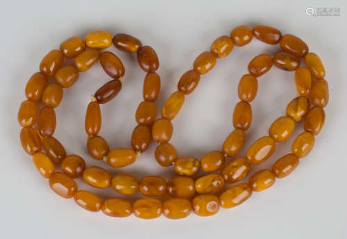 A single row necklace of sixty-two vari-coloured butterscotch semi-opaque and opaque oval amber