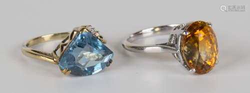 A 9ct gold, blue topaz and diamond ring, claw set with a fan shaped blue topaz and a row of three