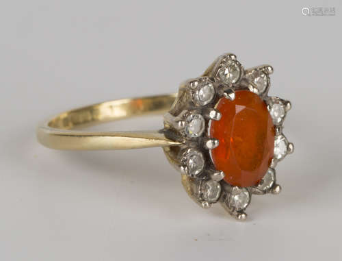 An 18ct gold, fire opal and diamond set oval cluster ring, claw set with the oval fire opal within a