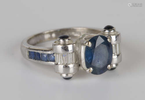 An 18ct white gold, sapphire and diamond ring, claw set with the principal oval cut sapphire between