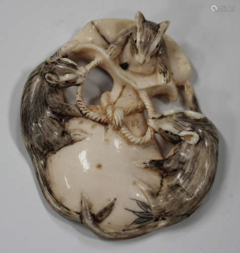 A Japanese ivory netsuke, Meiji/Taisho period, carved, pierced and stained with three rats upon a