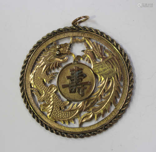A Chinese gold circular pendant, pierced and engraved with confronting dragon and phoenix, centred