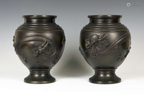 A pair of Japanese brown patinated bronze vases, Meiji period, each ovoid body cast in relief with a