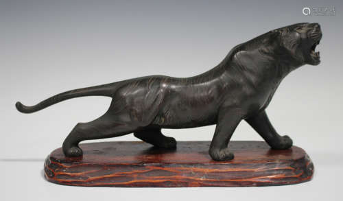 A Japanese brown patinated bronze model of a tiger, Meiji/Taisho period, modelled standing with