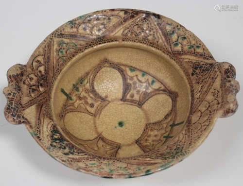 A Persian cream glazed pottery bowl, decorated with brown and green geometric decoration, width