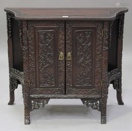 A Chinese hardwood side cabinet, late 19th/early 20th century, each panelled door carved in relief
