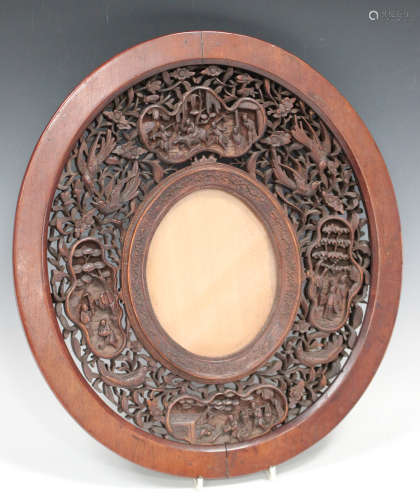 A Chinese Canton carved sandalwood oval photograph frame, late Qing dynasty, the surround carved and