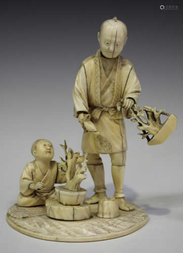 A Japanese carved sectional ivory okimono figure group of a father and son tending bonsai, Meiji
