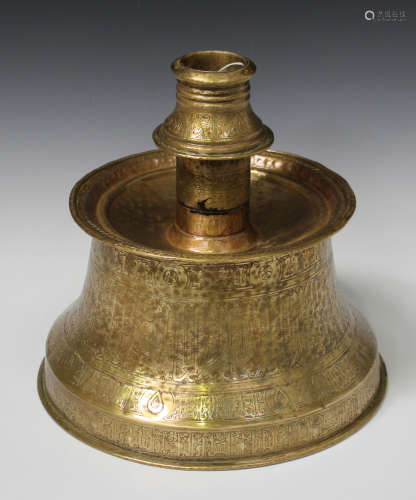 An Islamic brass candlestick, 13th century style but later, the waisted base rising to a dished