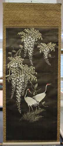 A Japanese silk embroidered hanging scroll, Meiji period, worked in coloured threads with a scene of