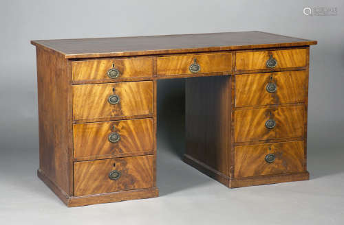 A George III figured mahogany twin pedestal desk, the crossbanded top inset with a gilt-tooled red