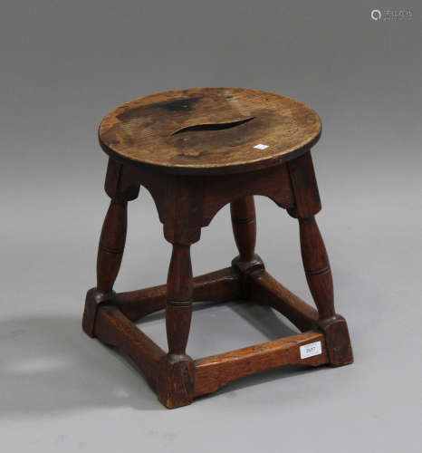 A 20th century oak stool, the circular pierced seat raised on turned and block legs united by