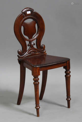 A late Victorian mahogany hall chair with carved and pierced decoration, the solid seat raised on