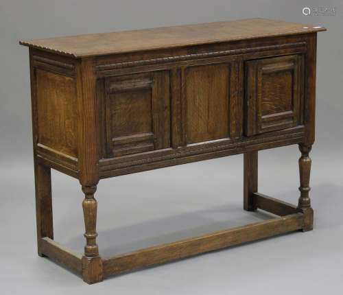 A 20th century oak dresser base, fitted with a pair of panelled doors, raised on turned and block