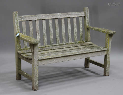 A late 20th century teak garden bench, the slatted seat and back raised on block legs, height