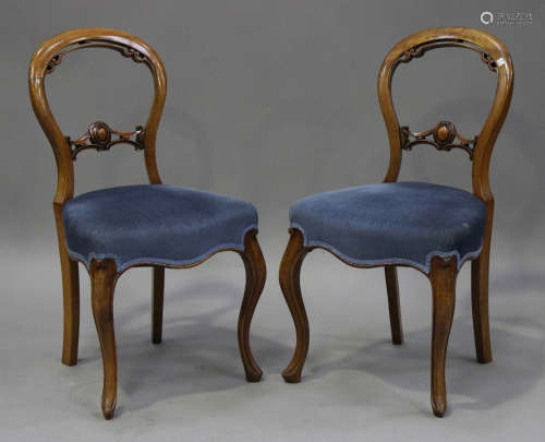 A set of six Victorian walnut spoon back dining chairs, the overstuffed seats on cabriole legs,
