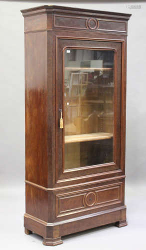 A late 19th century French walnut vitrine, the moulded pediment above an arch glazed door, the