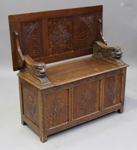 An early 20th century carved oak monk's bench, the triple panelled top above a box seat, on stile