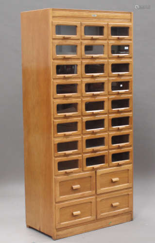 A mid-20th century pale oak haberdashery cabinet by Liddle, Keen & Co, London, fitted with twenty-