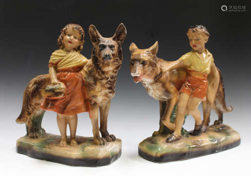A pair of Art Deco style plaster figures, modelled as a boy and girl, with an Alsatian dog,