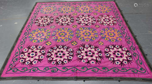A large Turkish suzani, the magenta silk ground with overall embroidered flowerheads, within a green