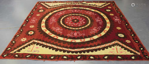 A large Turkish suzani, the woven claret and ivory ground worked with a central medallion, within