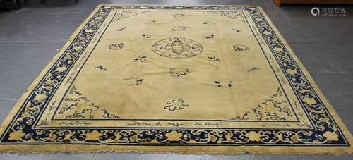 A Chinese carpet, late 19th/early 20th century, the pale yellow field sparsely decorated with a