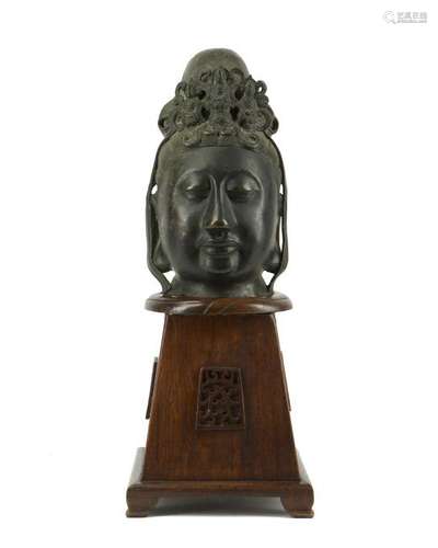 A bronze Quanyin head on wood stand