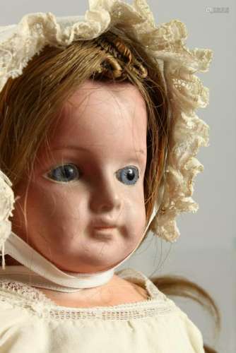 A SMALL BISQUE HEADED DOLL, with long hair, bonnet and