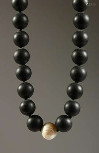 A HEAVY BLACK BEAD NECKLACE with a single pearl.