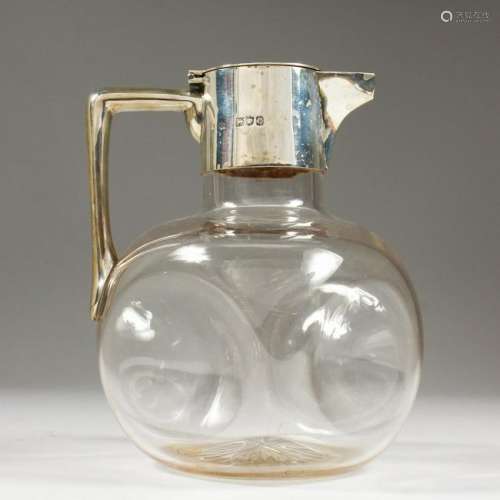 A PLAIN GLASS VICTORIAN CLARET JUG, with silver mounts.
