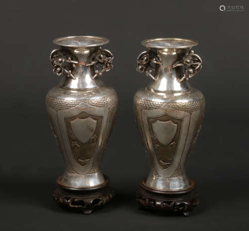 A pair of Japanese Meiji period silver baluster vases on carved hardwood plinths. With prunus