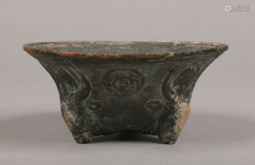 A Roman style terracotta bowl raised on three feet formed as ox masks, 13.75cm diameter.